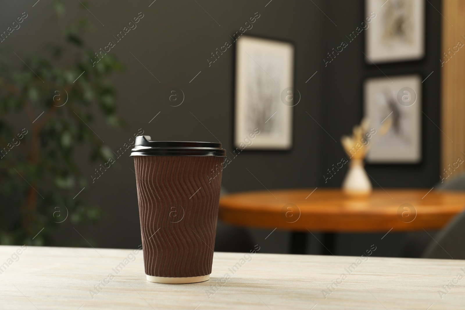 Paper cup on light wooden table in cafe. Mockup for design Photo of Paper cup on light wooden table in cafe. Mockup for design