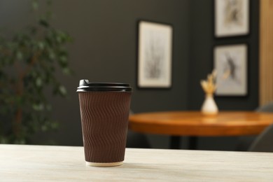 Photo of Paper cup on light wooden table in cafe. Mockup for design