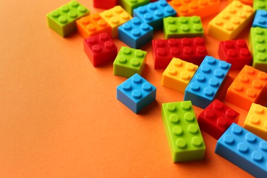 Photo of Construction toy. Colorful building bricks on orange background, closeup