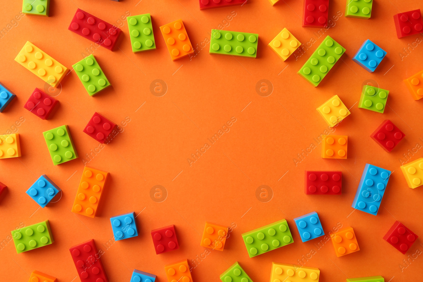 Photo of Frame of colorful building bricks on orange background, flat lay with space for text. Construction toy