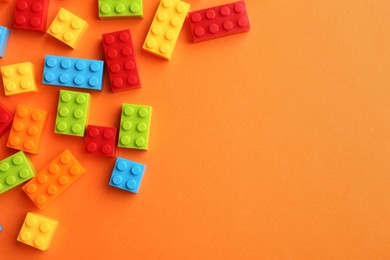 Photo of Construction toy. Colorful building bricks on orange background, flat lay with space for text