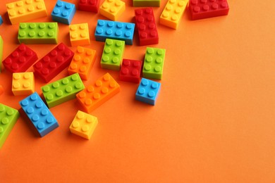 Photo of Construction toy. Colorful building bricks on orange background, space for text