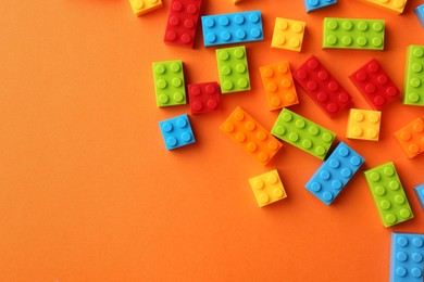 Photo of Construction toy. Colorful building bricks on orange background, flat lay with space for text