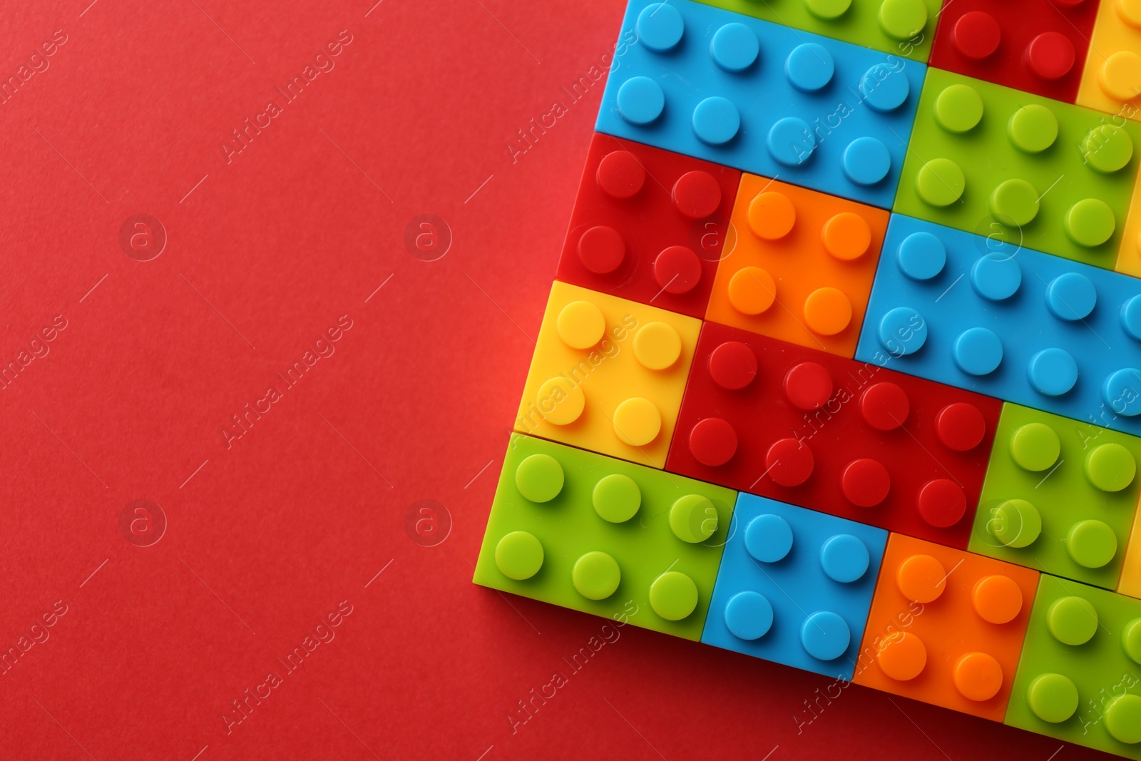 Photo of Construction toy. Colorful building bricks on red background, top view with space for text