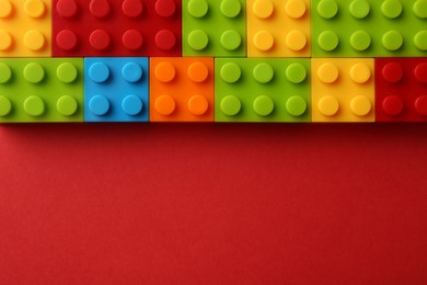 Photo of Construction toy. Colorful building bricks on red background, top view with space for text