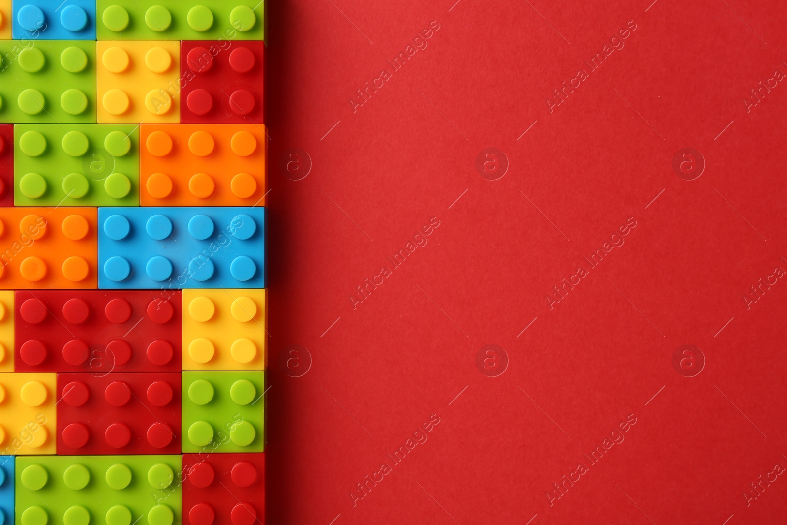 Photo of Construction toy. Colorful building bricks on red background, top view with space for text