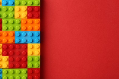 Photo of Construction toy. Colorful building bricks on red background, top view with space for text