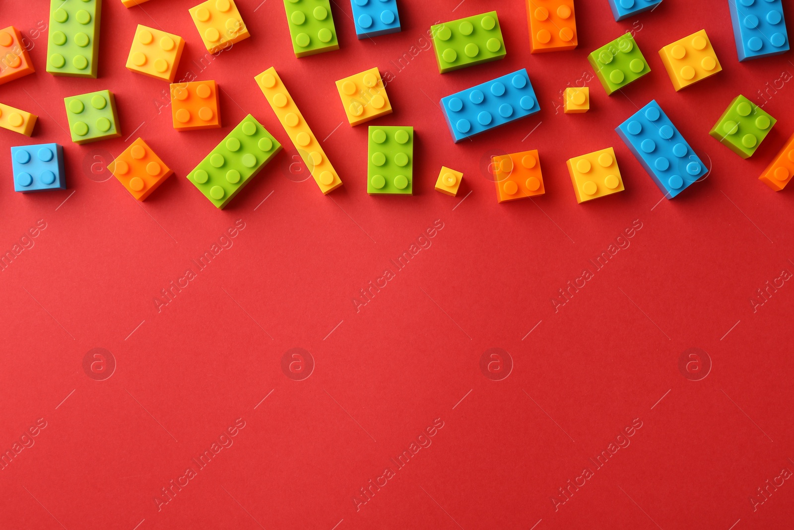 Photo of Construction toy. Colorful building bricks on red background, flat lay