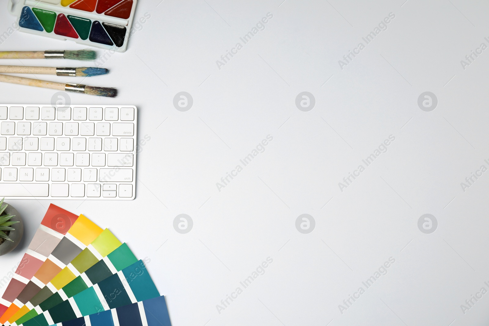 Photo of Designer's workplace with keyboard and stationery on light background, flat lay. Space for text