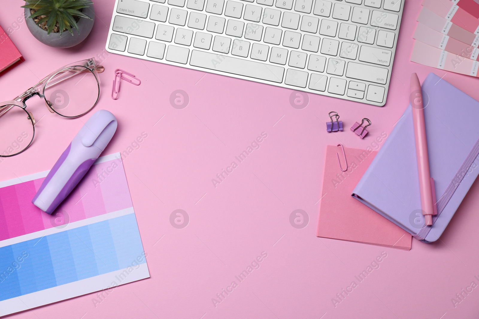 Photo of Designer's workplace with keyboard and stationery on pink background, flat lay. Space for text