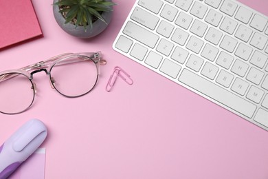 Photo of Designer's workplace with keyboard and stationery on pink background, flat lay. Space for text