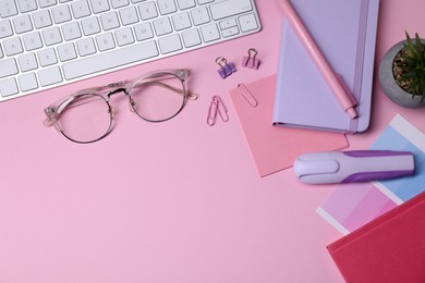 Photo of Designer's workplace with keyboard and stationery on pink background, flat lay. Space for text