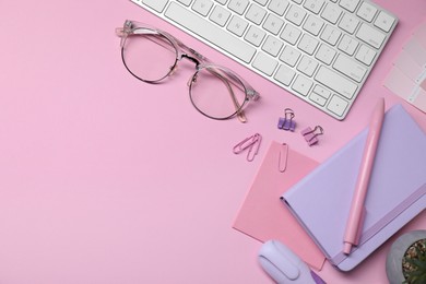 Photo of Designer's workplace with keyboard and stationery on pink background, flat lay. Space for text