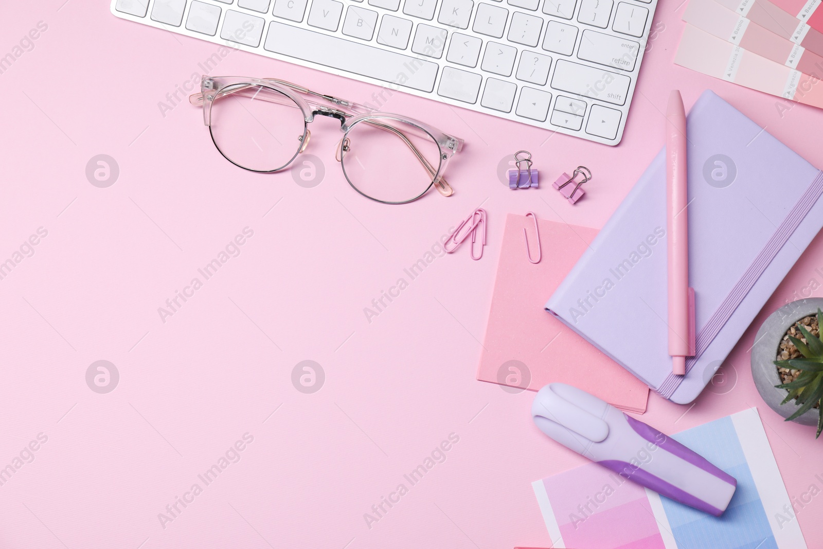 Photo of Designer's workplace with keyboard and stationery on pink background, flat lay. Space for text