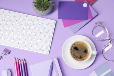 Photo of Designer's workplace with keyboard, stationery and cup of coffee on lilac background, flat lay