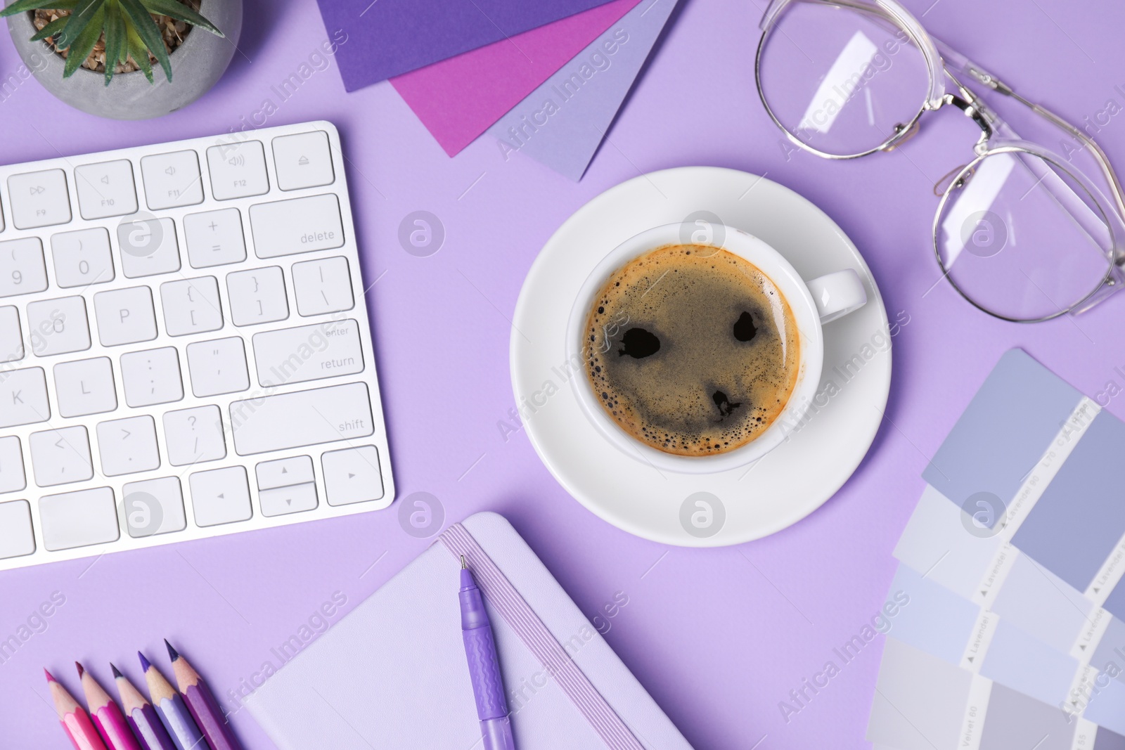 Photo of Designer's workplace with keyboard, stationery and cup of coffee on lilac background, flat lay