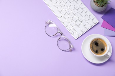 Photo of Designer's workplace with keyboard, stationery and cup of coffee on lilac background, flat lay. Space for text