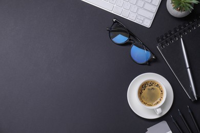 Photo of Designer's workplace with keyboard, stationery and cup of coffee on black background, flat lay. Space for text