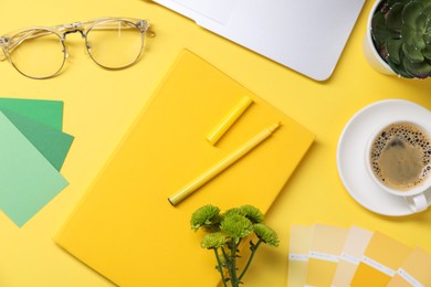 Photo of Designer's workplace with laptop, stationery and cup of coffee on yellow background, flat lay