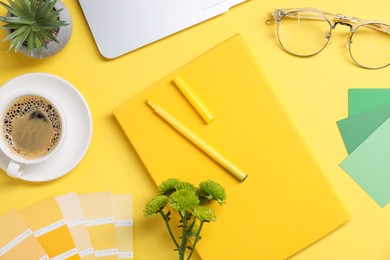 Photo of Designer's workplace with laptop, stationery and cup of coffee on yellow background, flat lay