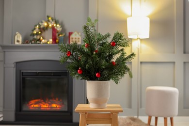 Photo of Beautiful Christmas composition of decorated fir tree branches on stool indoors