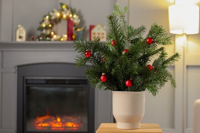 Photo of Beautiful Christmas composition of decorated fir tree branches on stool indoors