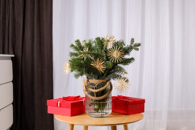 Photo of Beautiful composition of decorated fir tree branches and Christmas gifts on table indoors