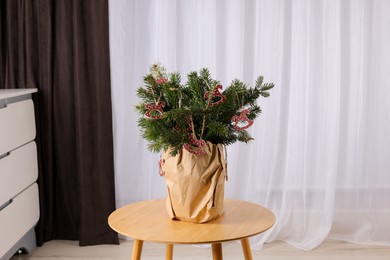 Photo of Beautiful Christmas composition of decorated fir tree branches on table indoors