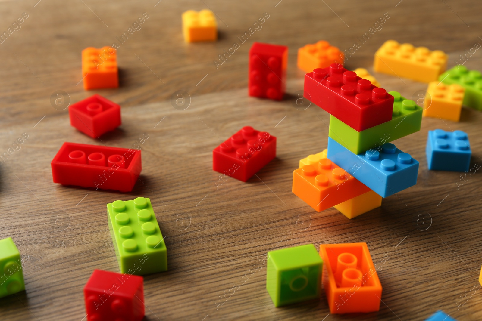 Photo of Construction toy. Colorful building bricks on wooden table, closeup