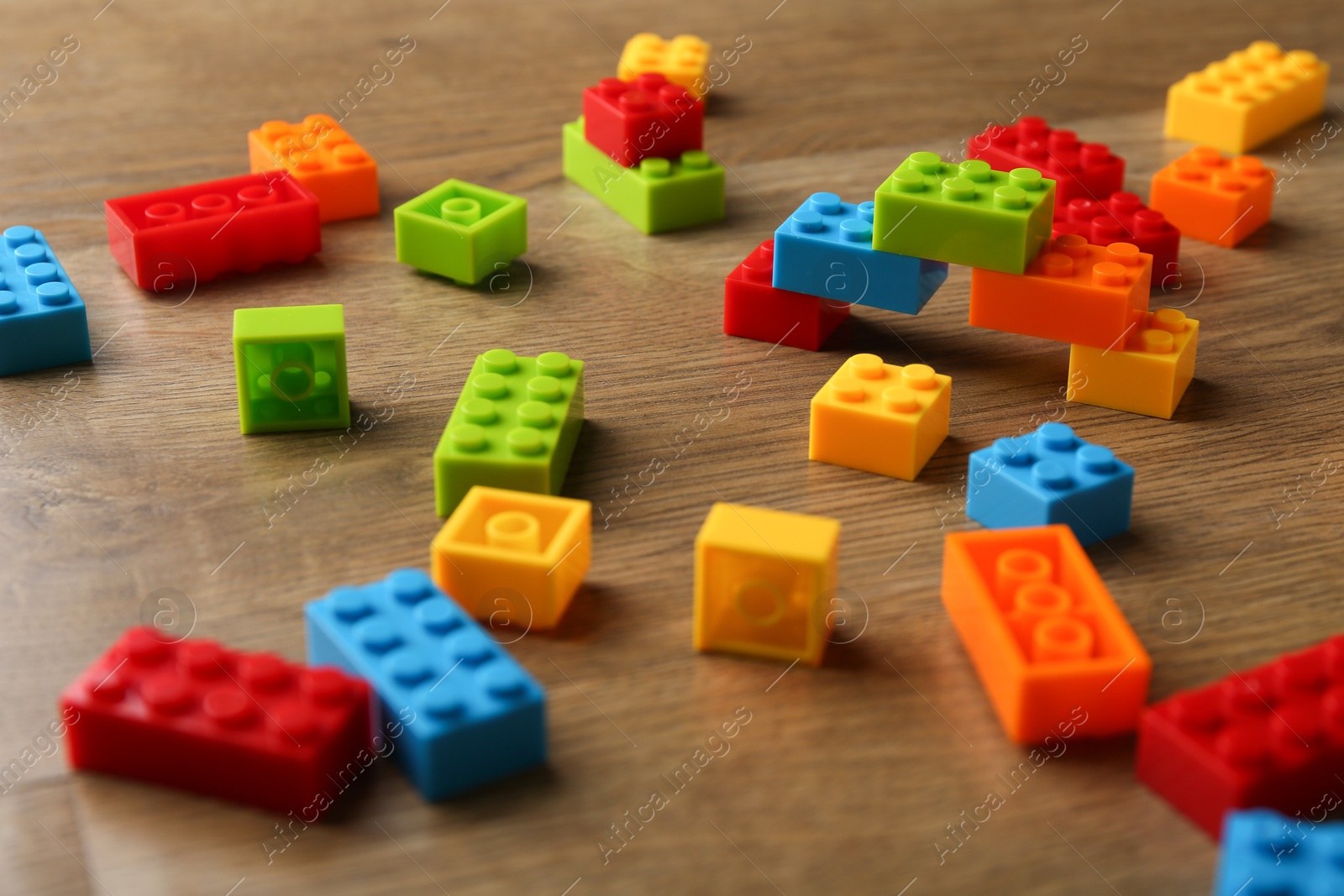 Photo of Construction toy. Colorful building bricks on wooden table, closeup