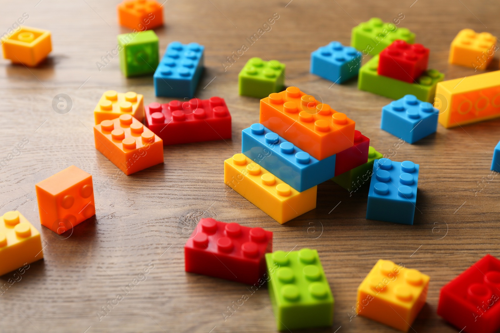 Photo of Construction toy. Colorful building bricks on wooden table, closeup