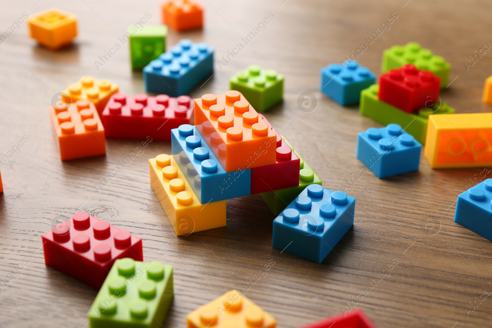 Photo of Construction toy. Colorful building bricks on wooden table, closeup