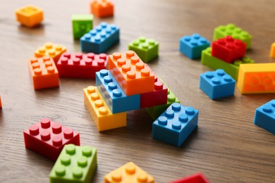 Photo of Construction toy. Colorful building bricks on wooden table, closeup