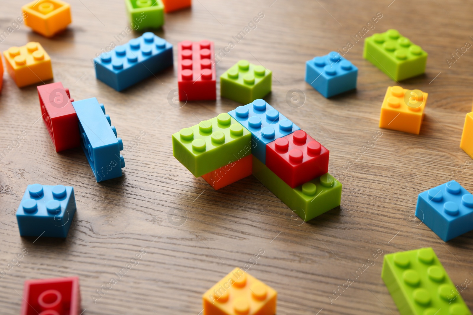 Photo of Construction toy. Colorful building bricks on wooden table, closeup