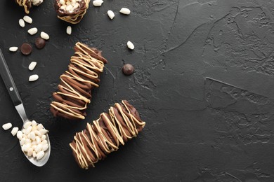 Photo of Delicious chocolate puffed rice bars and spoon on dark gray textured table, flat lay. Space for text