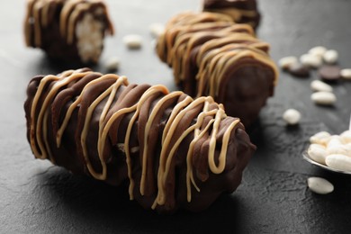 Photo of Delicious chocolate puffed rice bars on dark gray textured table, closeup