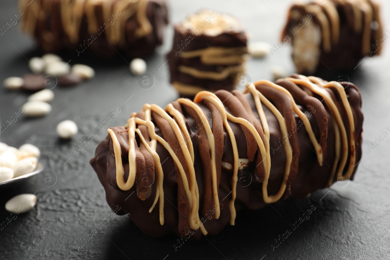 Photo of Delicious chocolate puffed rice bars on dark gray textured table, closeup