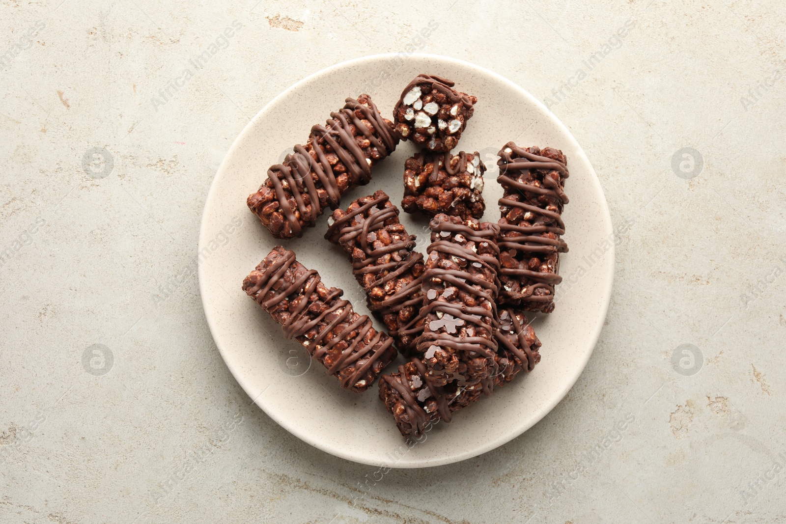 Photo of Delicious chocolate puffed rice bars on gray textured table, top view