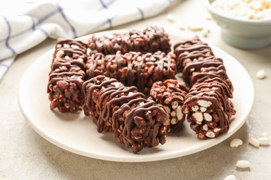 Photo of Delicious chocolate puffed rice bars on gray textured table, closeup