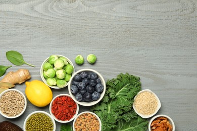 Photo of Superfood. Different healthy food products on grey wooden table, flat lay. Space for text