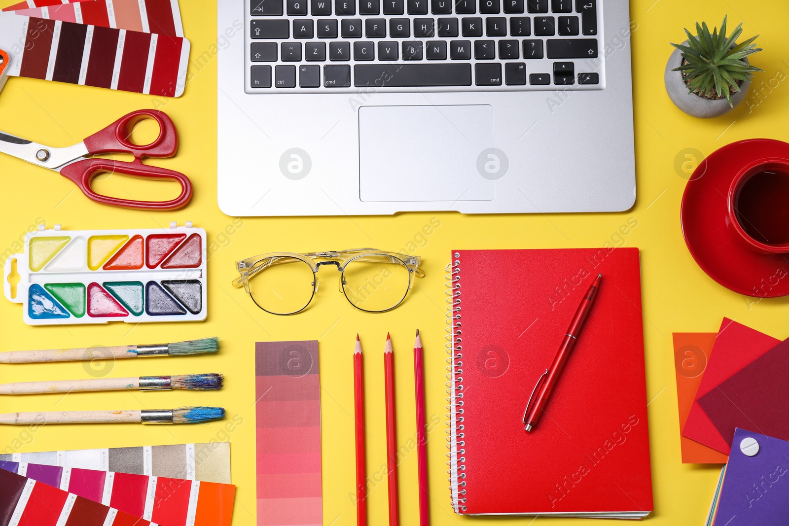 Photo of Designer's workplace. Flat lay composition with stationery, laptop and cup of coffee on yellow background