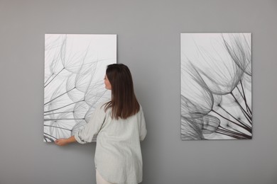 Photo of Woman hanging painting on wall in art gallery, back view