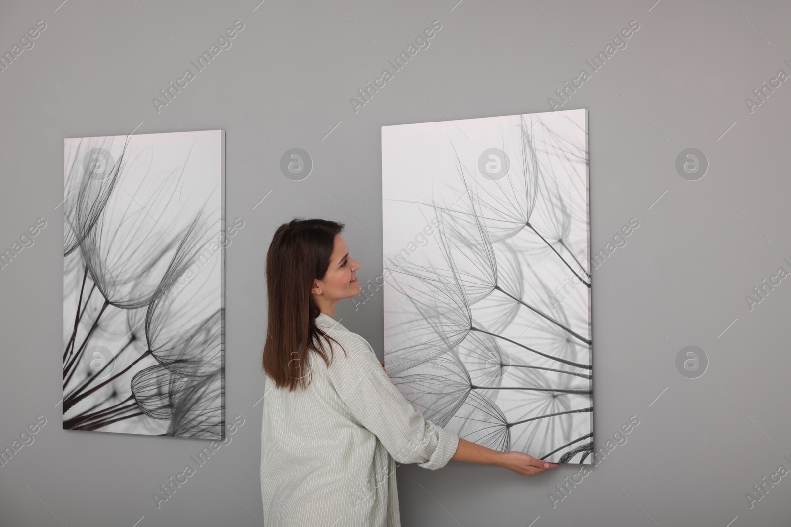 Photo of Woman hanging painting on wall in art gallery