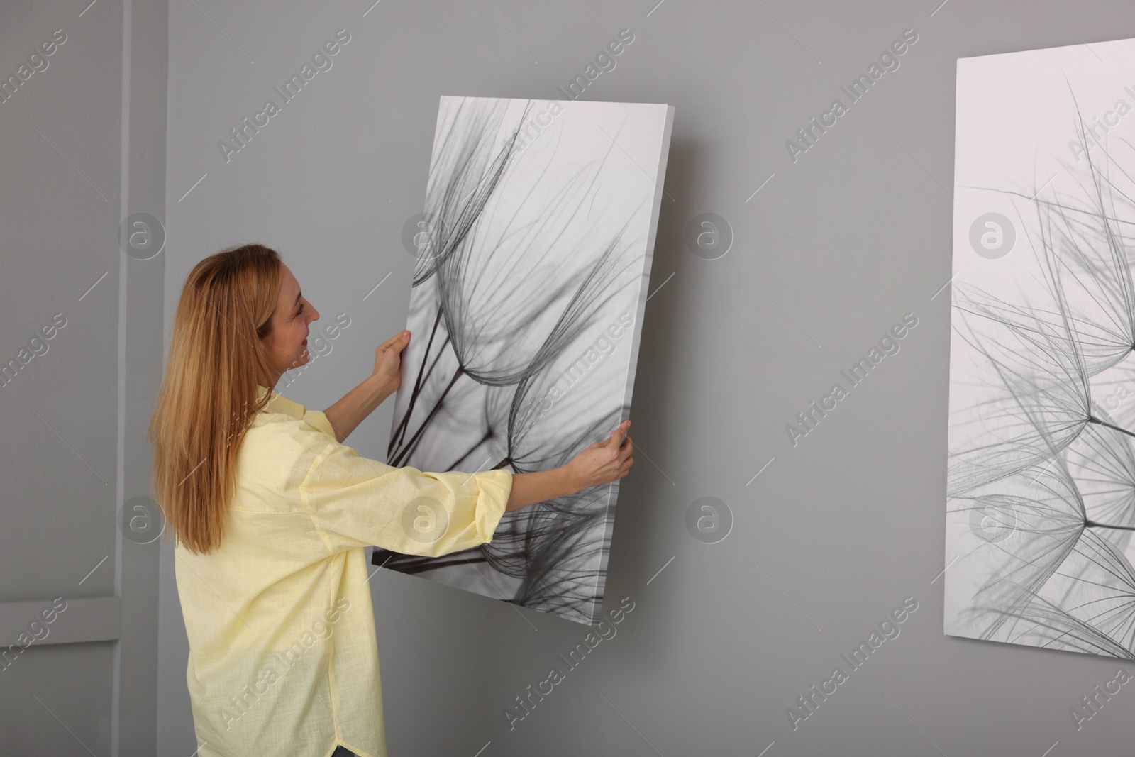 Photo of Woman hanging painting on wall in art gallery