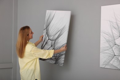 Photo of Woman hanging painting on wall in art gallery