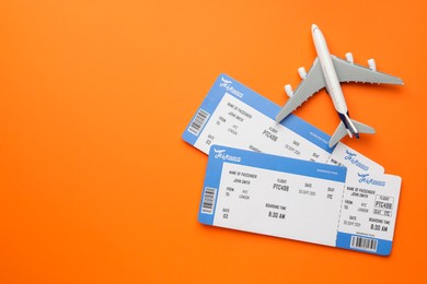 Photo of Travel agency. Flight tickets and plane model on orange background, flat lay. Space for text