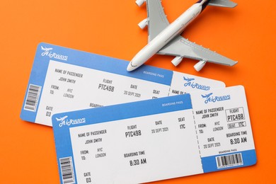 Photo of Travel agency. Flight tickets and plane model on orange background, flat lay