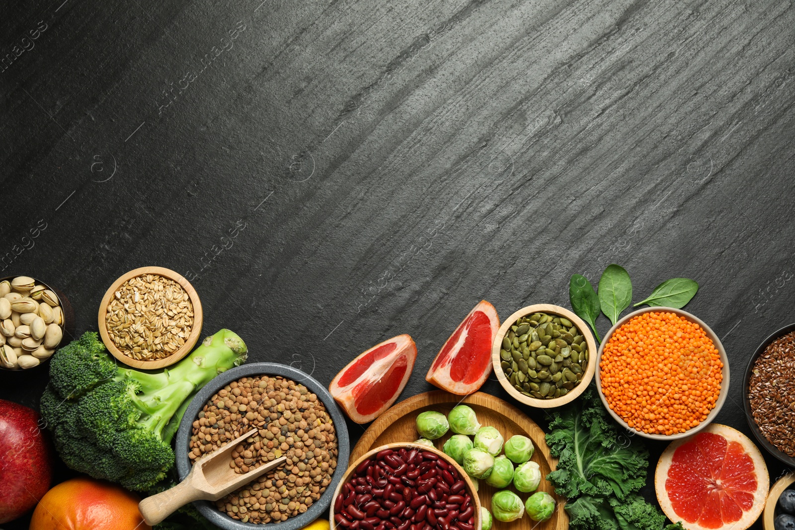 Photo of Different superfood products on black table, flat lay. Space for text