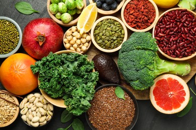 Photo of Different superfood products on black table, flat lay