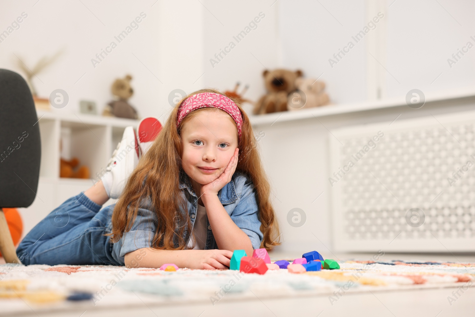 Photo of Little girl playing with balancing stones on floor indoors, space for text